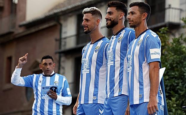 Three Malaga players pose with the new top. 