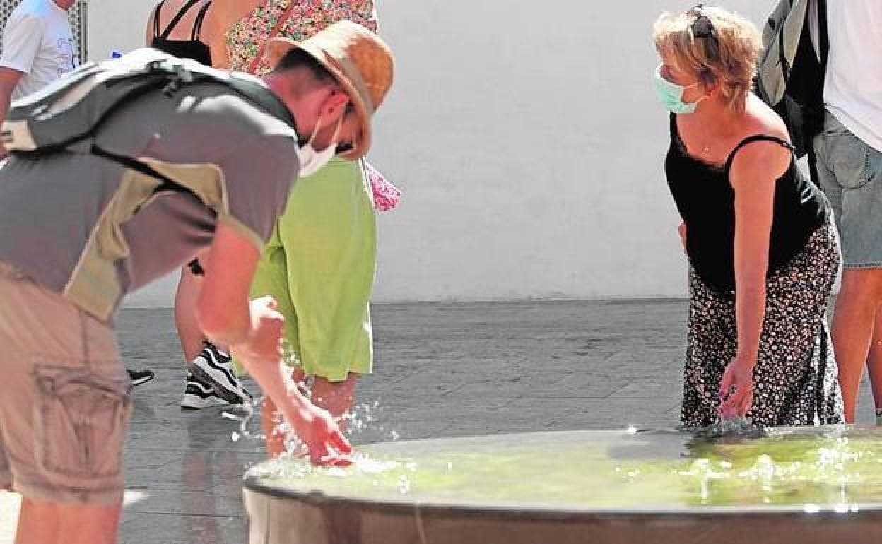 Tourists cool down in a fountain in Malaga city. 