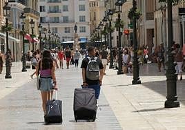Tourists make their way to their accommodation in Malaga city centre.
