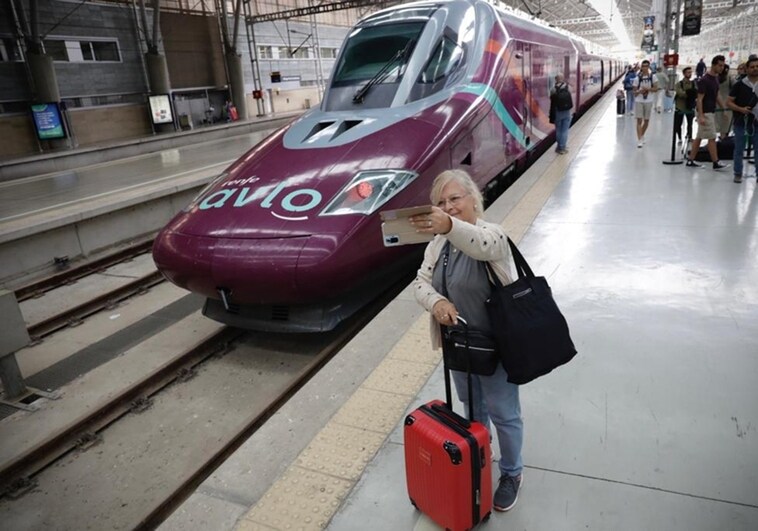 A traveller takes a photo with the new train in the background.