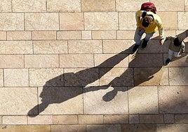 A parent walking with a child in Malaga on a sunny day.