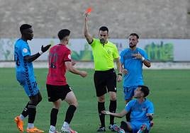 A referee holds up a red card at a match.
