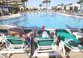 Tourists relax on the sun loungers by the pool of a Costa del Sol hotel.