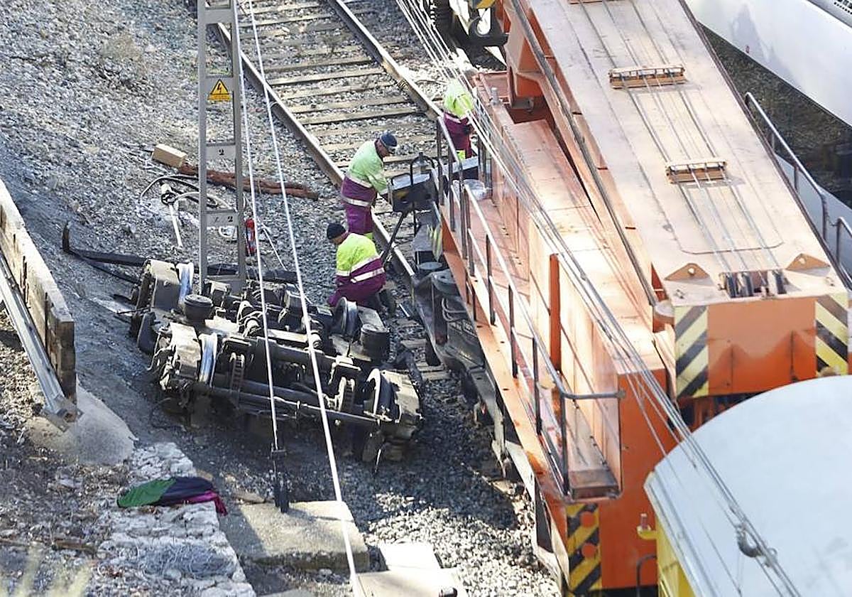 Workers attempt to clear the damaged trains from the tracks at El Chorro railway station this Monday, 18 December.
