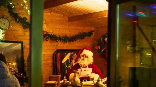 Father Christmas reads letters from children in his study.