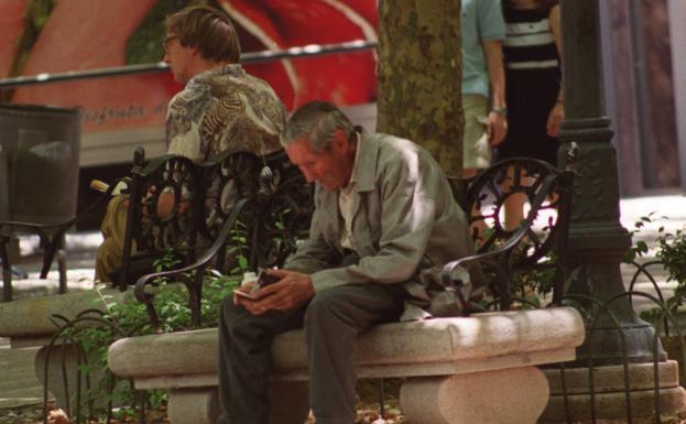 An elderly man sat alone on a bench. 