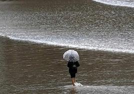 File image of a woman walking along a beach in the north of Spain.