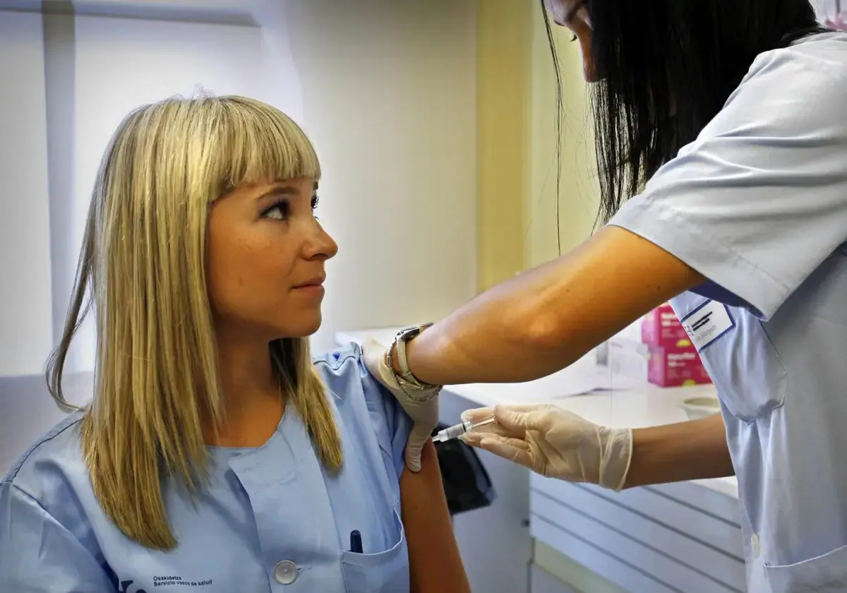A nurse at a health centre gives a dose of flu vaccine to a colleague.