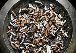 Ashtray littered with cigarette butts outside an office building.