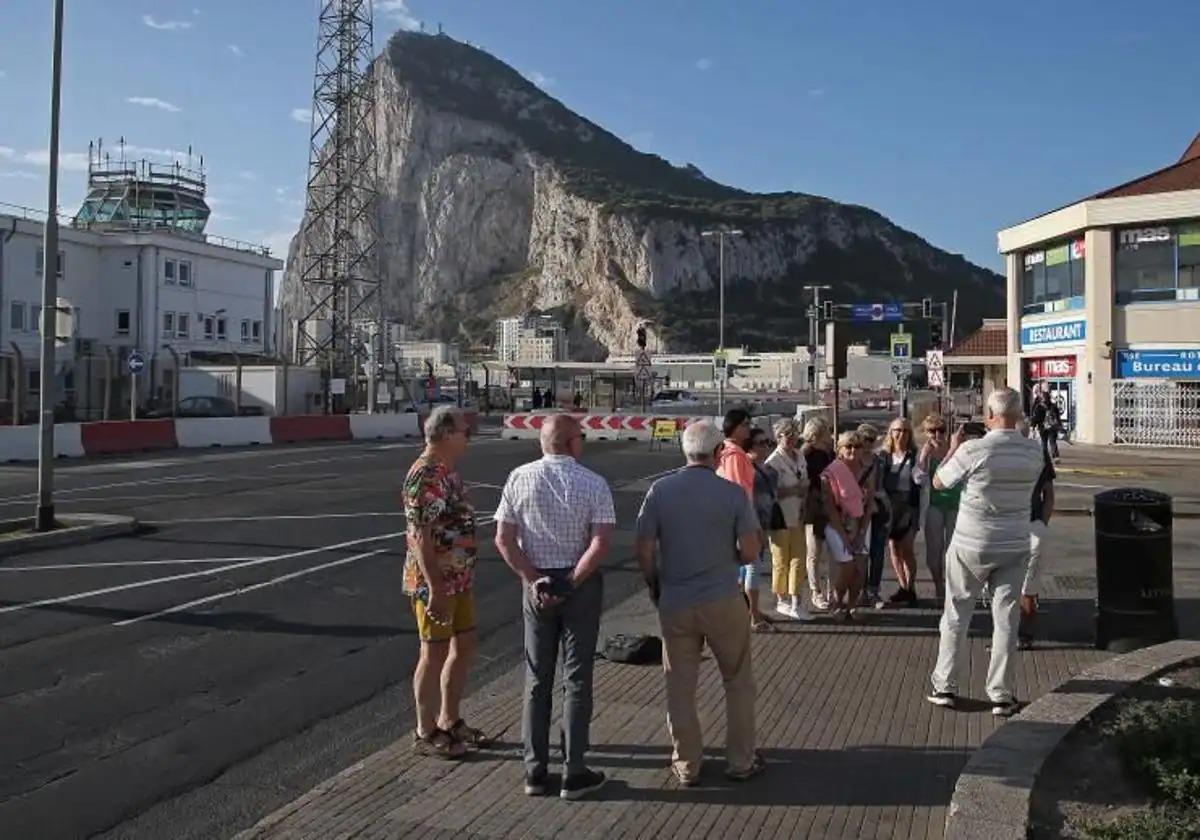 A group of people pose for a photo with the Rock behind them.