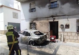 Firefighters with the burnt-out car in Alfarnate.