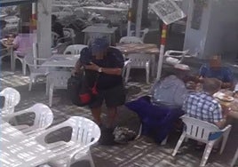 Screenshot of the video showing the alleged thief dragging one of the bags from the table with his foot