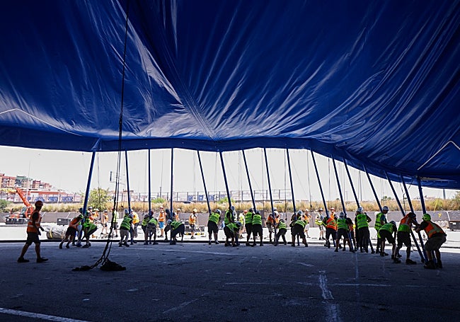 Some 60 people lift more than a hundred poles to raise the tarpaulin.