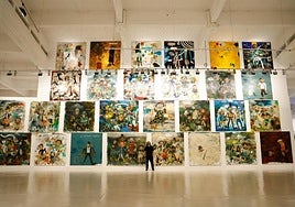 Matías Sánchez in front of a giant wall covered in his most ambitious works.