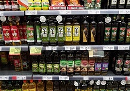 Supermarket shelf with bottles of olive oil.