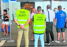 Two taxi staff monitor the exit from the terminal to prevent pirates from picking up tourists.