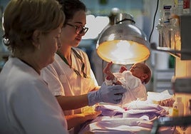 Two nursing staff with a newborn baby.