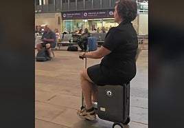 A woman riding on a motorised suitcase at Seville's Santa Justa railway station.