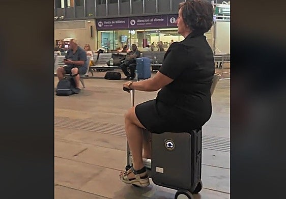 A woman riding on a motorised suitcase at Seville's Santa Justa railway station.