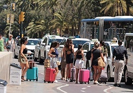 Tourists wait with their luggage at a taxi rank in Malaga city centre.