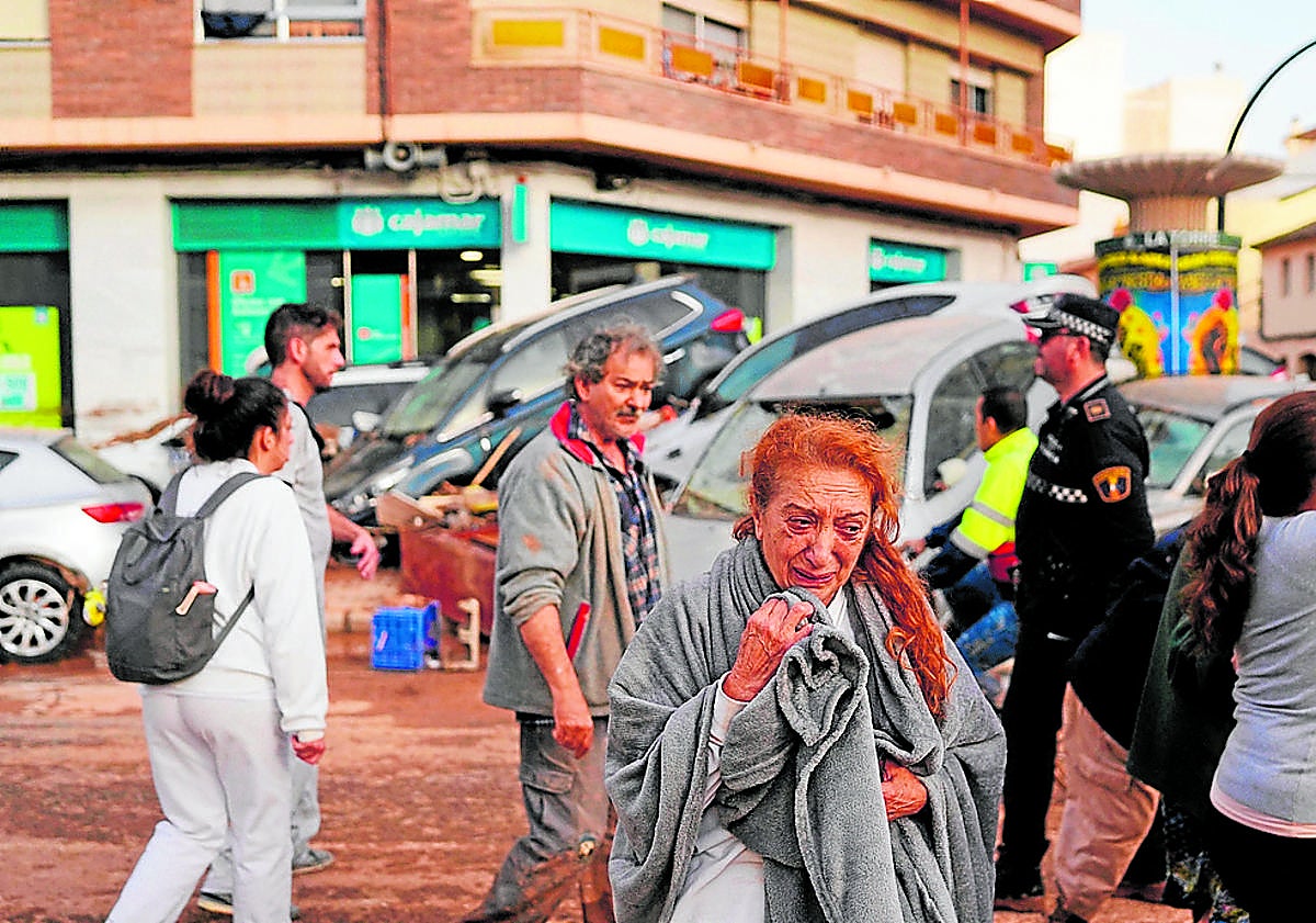Imagen principal - From top: A woman weeps in a devastated street in the Valencian town of Sedaví, rescuers in Mira in Cuenca (Castilla- La Mancha) and a person is evacuated in Letur (Castilla-La Mancha). 