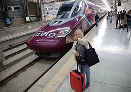 A passenger takes a selfie in front of an Avlo train at Malaga station.