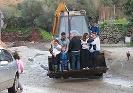 Families get a lift on an excavator, the only viable means of transport in some of the places scattered around Almogía.