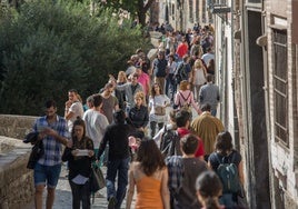 Dozens of tourists walk along the Paseo de los Tristes in Granada.