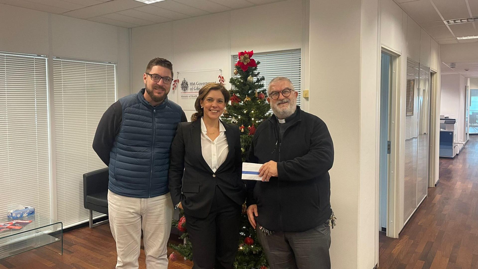 Care Agency staff present the cheque to Father Charlie.