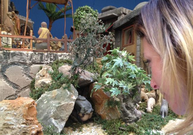 A visitor looks at the caganer in a Nativity scene.