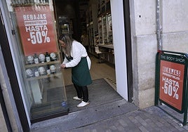 A shop assistant preparing a window display for last year's sales.