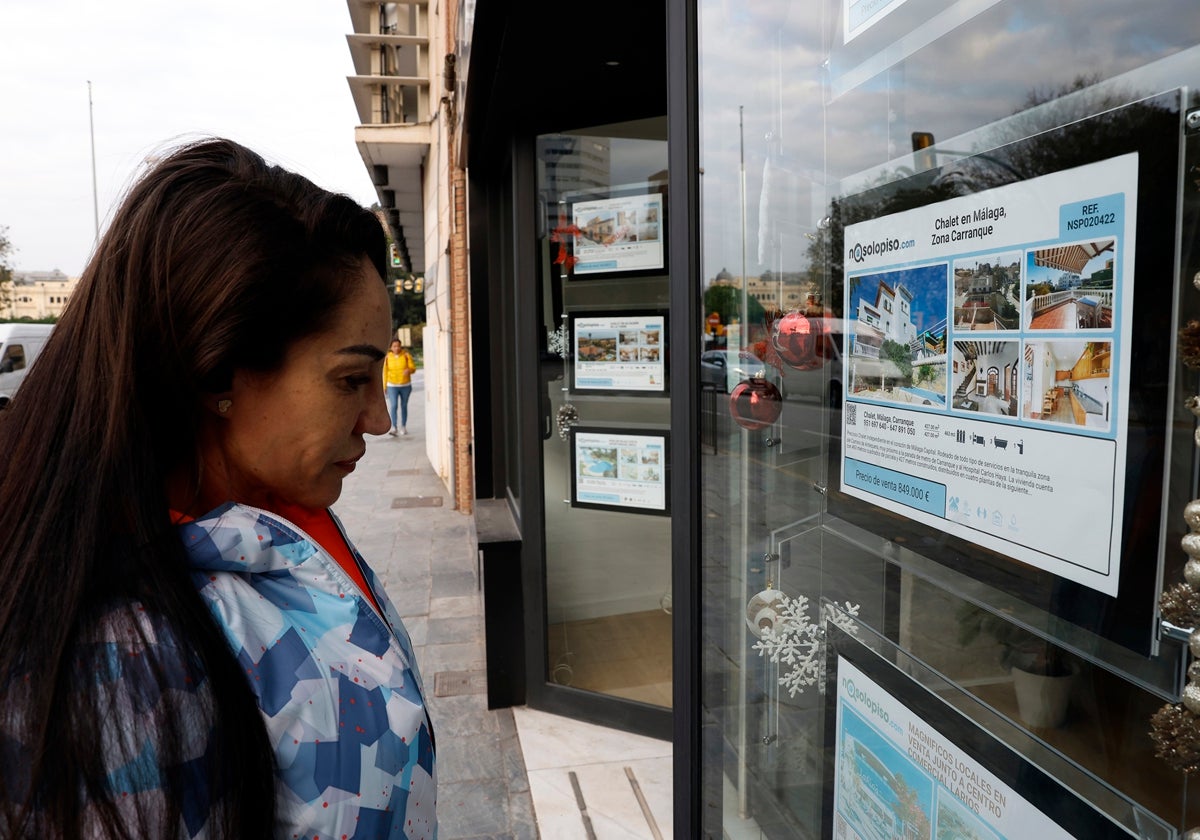 A passer-by looks at the offer of flats in a real estate agency window.