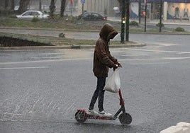 A youth rides an electric scooter in the rain.
