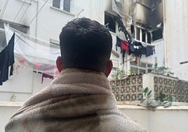 Mohamed looks out from his courtyard at his neighbours' burnt flat.
