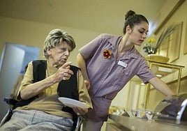 An auxiliary helps a person in a nursing home to choose the food she is going to eat.
