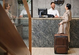 A hotel receptionist attends to a tourist.
