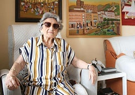 Trinidad in her living room, in front of three of the pictures she painted after beginning her art career at the age of 70.
