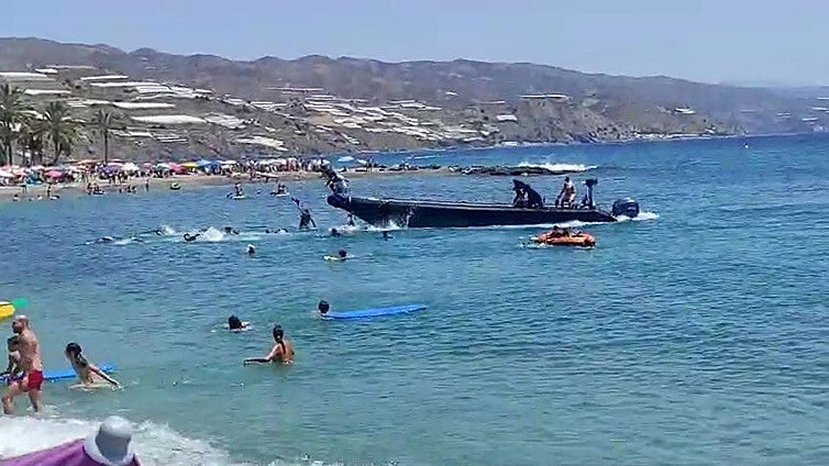 The is the moment 'dozens' of illegal immigrants disembarked from a people-smuggling boat in broad daylight on a packed beach in Spain