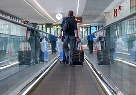 Passengers with carry-on luggage at a Spanish airport.
