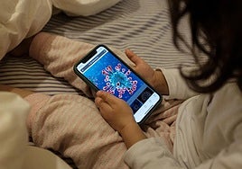 A young girl uses her mobile phone in bed.