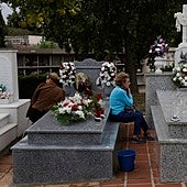 Two women keep vigil by their loved ones' graves at Malaga's San Gabriel cemetery.