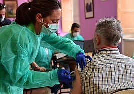 A nurse gives an elderly patient his flu jab.