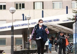 A woman leaves the hospital emergency room wearing a mask.