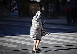 A woman shields herself against the cold weather in Malaga with thick coat.