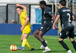 Villarreal B's Hugo López protects the ball under pressure from Torremolinos's Usse Diao.
