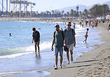 Tourists strolling along the beach in Malaga city.