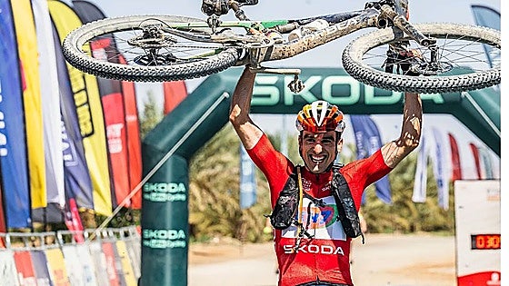 Maté lifts his bike after crossing the finishing line.