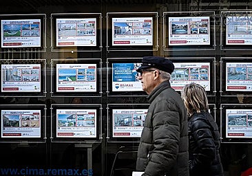 A couple passing in front of a real estate agency in Spain.