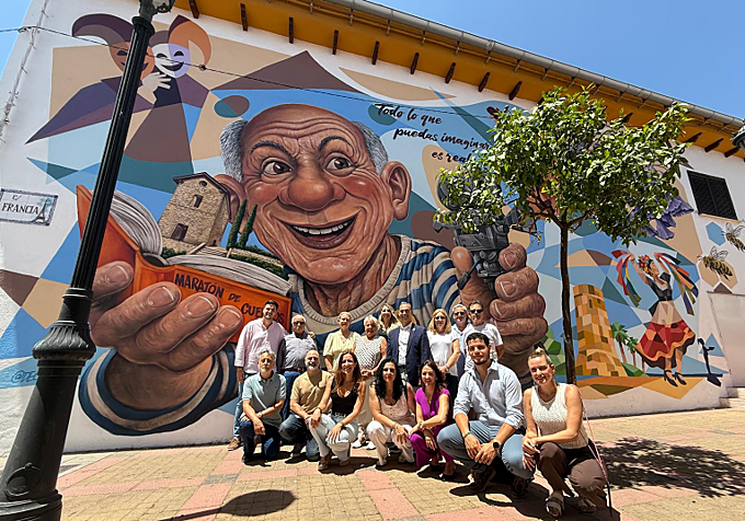 Local associations and community groups pose in front of another new mural in Arroyo de la Miel.