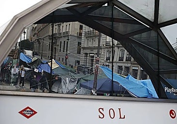 Tents reflected in the glass at the entrance to Sol station in Madrid.